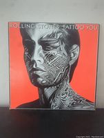 Front cover of Rolling Stones Tattoo You record showing tattooed male portrait on a red background
