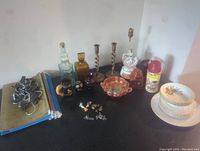 Wide view of lot showing Ridgeway plates and bowls stacked, glass bottles, amber jars, spiral metal candlesticks, ceramic lamp, various pins, Roy Rogers thermos, hangers and file folders.