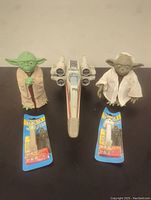 All five items displayed: two Yoda figurines on either side of the X-wing jet fighter, and two Pez dispensers (Yoda and Stormtrooper) in front.