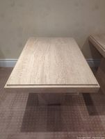 Front view of travertine table top and base combined, showing rectangular table surface and underlying solid base.