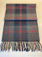 Full view of the folded scarf showing the plaid pattern and fringed ends.