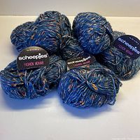 Seven balls of blue yarn with nubbly multicolor accents, some with original Scheepjes Fashion Mohair tags.