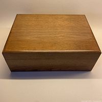 Front view of the rectangular solid wood box with closed lid.