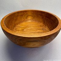 Front angled view of a large hand turned wooden bowl showing natural wood grain and smooth finish.