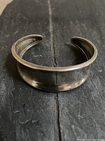 Front view of a concave sterling silver cuff bracelet showing the wide center section tapering to the opening.
