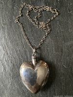 Full view of heart pendant on chain laid flat