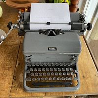 Front view of the vintage gray Royal typewriter with a paper loaded in it, showing keys and logo.