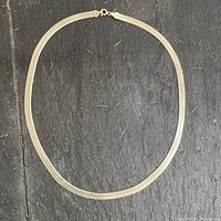 Full view of the chunky snake chain necklace laid flat on a dark surface showing length and width.
