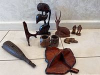 Photo showing entire lot with various carved wood items arranged on tile floor