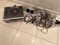 Full view of the stereo receiver, speakers, and large bundle of various audio and power cables laid out on floor.