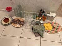 Overview of all items on floor including glass jars, glasses, serveware, candle holders, placemats, and tablecloths