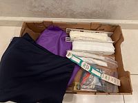 Shows three fabric remnants in box including navy blue, purple, and brown wool with moth holes, plus lace trim and zippers.