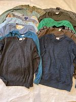 Several sweaters and tops folded, showing variety of colors and styles including solid and patterned knits.