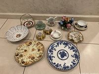 Overview of assorted porcelain and stoneware items including plates, cups, bowls, and the flower figurine