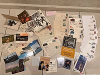Overview photo showing a wide collection of black and white photos, color postcards, first day covers, sports cards, envelopes, and other ephemera spread on a flat surface