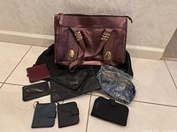 Full view of the leather purse with the accompanying wallets, coin pouch, cosmetic bags laid out around it on a tiled floor.
