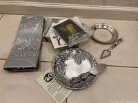 Photo showing all items: silver-plated candy dish with grapevine design and serving utensil, silver plated small plate, cheese plate with utensil, wine gift bags, and string art cards.