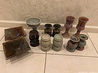 Full set of 12 hand-glazed stoneware pottery items arranged on floor, showing variety of pieces and colors