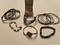 Full lot showing variety of bracelets and included pair of clip-on earrings in box