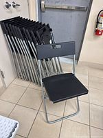 Single chair unfolded in front of a stack of chairs to show design