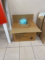 Cardboard master carton open with visible aqua blue round gift boxes wrapped in plastic inside.