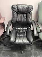 Front view of black office desk chair showing padded seat and backrest upholstered in black leather or leather-like material.