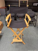 Front view of black and wood directors chair with canvas seat and backrest, wooden armrests, and foldable X-frame.