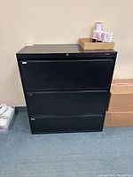 Front view of the black three drawer filing cabinet showing all drawers closed with lock mechanism on top drawer.