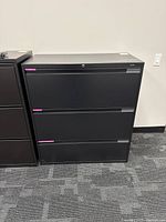Front view of black 3-drawer filing cabinet with lock on top drawer.