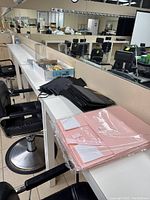 Black wine bags and pink gift boxes stacked on a counter in a room with salon chairs and mirror visible