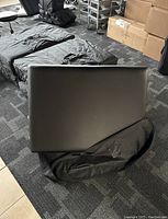 Folded portable black massage table showing padded surface.