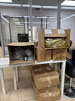 Cardboard boxes containing silver and gold Mylar shredded foil and tinsel displayed on table.