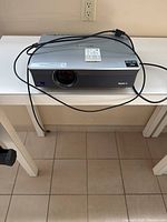 Front view of Sony projector with lens, power cable, and remote laying on top