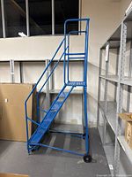 Left side view of blue rolling ladder showing frame and wheel