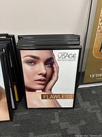 Twelve black poster frames stacked showing front with a poster of a woman's face and the word 'FLAWLESS'.