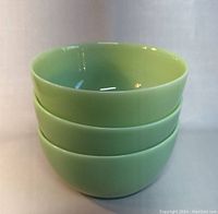 Stack of three light green opaque jadeite bowls showing bright glossy finish and good condition.