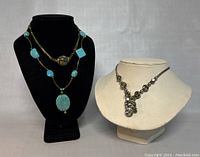 Front view of all three necklaces on display busts showing turquoise bead necklace, silver-tone necklace with stones, and dark bead necklace with turquoise pendant.