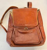 Front view of vintage brown leather backpack with flap and front zippered pocket