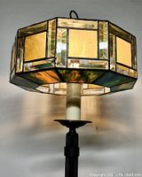 Close-up of Tiffany style stained glass shade showing rectangular amber panels and beveled clear and green glass border