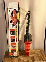 Black & Decker Cordless Hedge Trimmer upright with its box, showing the blade and handle