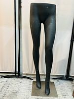 Front view of black female lower body mannequin legs on a metal stand showing light surface wear.