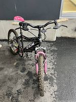 Front angled view of the black and pink CCM kids bicycle showing handlebars, front tire, and part of the frame.