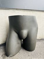 Front angled view of black male lower body mannequin showing scratches and wear on thigh and hip.