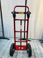 Front view of red Milwaukee hand truck in vertical two-wheel mode with puncture proof tires.