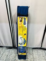 Photo of the folded portable gazebo stored in a blue carrying bag with product information label visible.