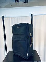 Front-side view of black suitcase showing two zippered compartments and telescopic handle extended.