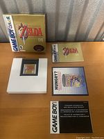 All items laid out: box upright at back, cartridge in insert, manual, consumer booklet, promotional leaflet