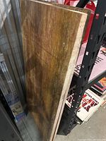 Photo showing the side view of a large, thick marble slab with natural brown and reddish tones leaning against shelving.