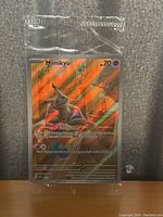 Photo of Mimikyu promo trading card sealed in protective plastic sleeve, showing holographic foil detail and card front