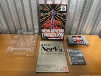 Front view of boxed Neon Genesis Evangelion N64 game, cartridge, manuals, and plastic tray on wooden surface
